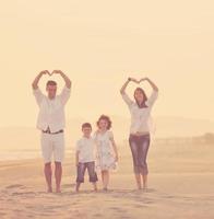 contento giovane famiglia avere divertimento su spiaggia a tramonto foto