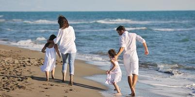 contento giovane famiglia avere divertimento su spiaggia foto