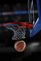 palla da basket e rete su sfondo nero foto
