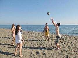 giovane persone gruppo avere divertimento e giocare spiaggia pallavolo foto