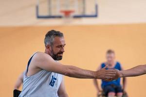 un' squadra di guerra veterani nel sedie a rotelle giocando pallacanestro, festeggiare punti ha vinto nel un' gioco. alto cinque concetto foto