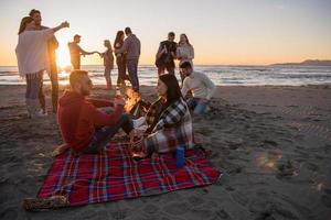 coppia godendo con amici a tramonto su il spiaggia foto