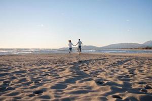 coppia con cane avendo divertimento su spiaggia su autunno giorno foto