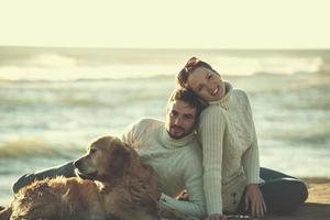 coppia con cane godendo tempo su spiaggia foto