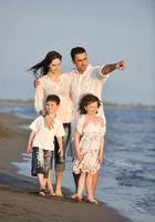 contento giovane famiglia avere divertimento su spiaggia a tramonto foto