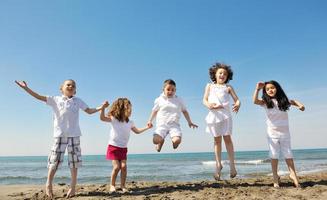 gruppo di bambini felici che giocano sulla spiaggia foto