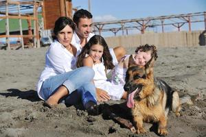 contento famiglia giocando con cane su spiaggia foto