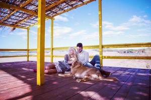 coppia con cane godendo tempo su spiaggia foto