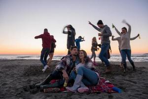 coppia godendo con amici a tramonto su il spiaggia foto