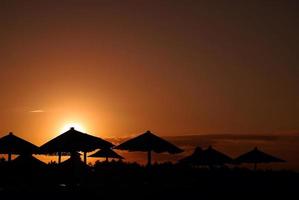 luce del sole su spiaggia con spiaggia ombrelli silhouette foto