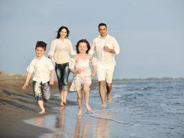 contento giovane famiglia avere divertimento su spiaggia a tramonto foto