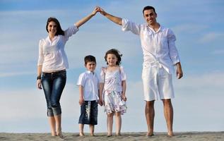 famiglia su spiaggia mostrando casa cartello foto