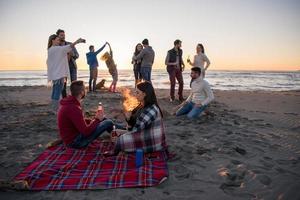 coppia godendo con amici a tramonto su il spiaggia foto