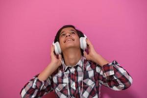 Arabo adolescenziale ragazzo indossare cuffie e ascoltando per musica rosa sfondo foto