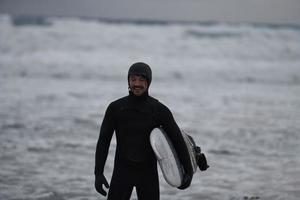 artico surfer andando di spiaggia dopo fare surf foto