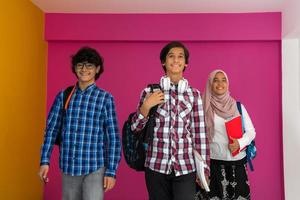 un' gruppo di arabo adolescenti, un' alunno squadra a piedi inoltrare in il futuro e indietro per scuola il concetto di un' rosa sfondo. il concetto di riuscito formazione scolastica per giovane le persone. selettivo messa a fuoco foto