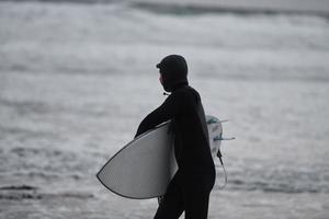 artico surfer andando di spiaggia dopo fare surf foto