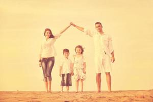 famiglia su spiaggia mostrando casa cartello foto