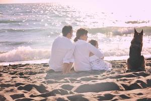 contento famiglia giocando con cane su spiaggia foto