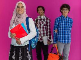 un' gruppo di arabo adolescenti, un' alunno squadra a piedi inoltrare in il futuro e indietro per scuola il concetto di un' rosa sfondo. il concetto di riuscito formazione scolastica per giovane le persone. selettivo messa a fuoco foto