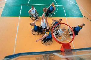 Disabilitato guerra o opera veterani misto gara e età pallacanestro squadre nel sedie a rotelle giocando un' formazione incontro nel un' gli sport Palestra sala. portatori di handicap persone reinserimento e inclusione concetto. foto