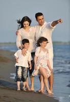 contento giovane famiglia avere divertimento su spiaggia a tramonto foto