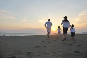 contento giovane famiglia avere divertimento su spiaggia a tramonto foto