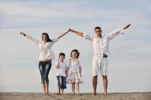 famiglia su spiaggia mostrando casa cartello foto