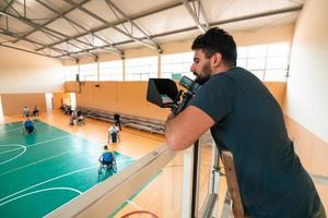 un' cineoperatore con professionale attrezzatura record un' incontro di il nazionale squadra nel un' sedia a rotelle giocando un' incontro nel il arena foto