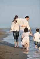 contento giovane famiglia avere divertimento su spiaggia a tramonto foto