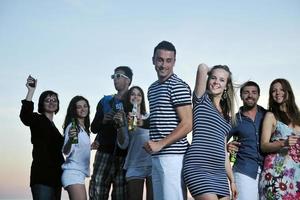 gruppo di giovane persone godere estate festa a il spiaggia foto