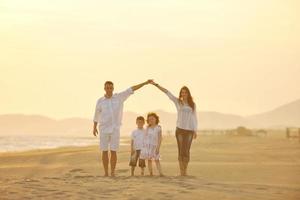 contento giovane famiglia avere divertimento su spiaggia a tramonto foto