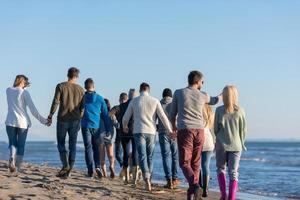 gruppo di amici in esecuzione su spiaggia durante autunno giorno foto