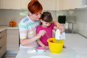 divertente poco ragazza aiutante giocando con Impasto su il suo mani apprendimento per impastare aiuta adulto mamma nel il cucina, contento carino bambino figlia e genitore mamma avere divertimento cucinando biscotti. foto