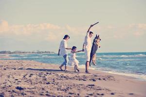 contento famiglia giocando con cane su spiaggia foto
