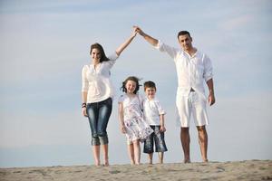 famiglia su spiaggia mostrando casa cartello foto