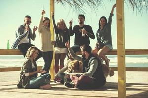 gruppo di amici avendo divertimento su autunno giorno a spiaggia foto