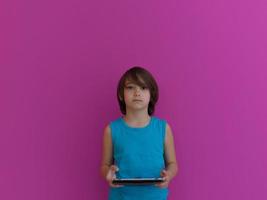 poco arabo ragazzo utilizzando su digitale tavoletta rosa sfondo foto