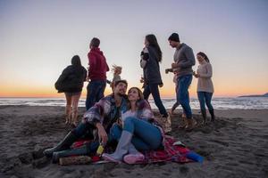 coppia godendo con amici a tramonto su il spiaggia foto