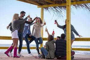 gruppo di amici avendo divertimento su autunno giorno a spiaggia foto