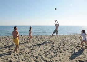 giovane persone gruppo avere divertimento e giocare spiaggia pallavolo foto