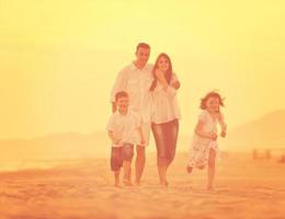 contento giovane famiglia avere divertimento su spiaggia a tramonto foto