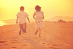 contento giovane famiglia avere divertimento su spiaggia a tramonto foto