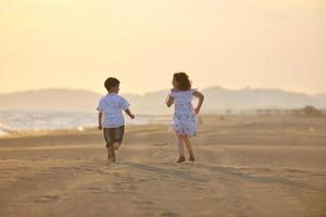 contento giovane famiglia avere divertimento su spiaggia a tramonto foto