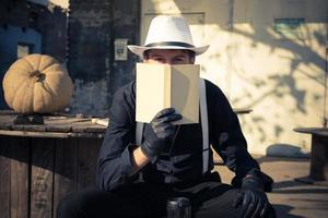 uomo nel nero sbirciando dietro a il libro. foto