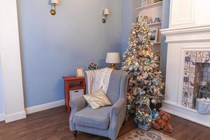 classico Natale decorato interno camera, nuovo anno albero con argento decorazioni. moderno blu classico stile interno design appartamento con camino e poltrona. Natale vigilia a casa. foto