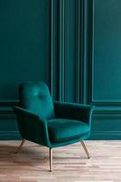 bella camera interna pulita di lusso classico blu verde in stile classico con poltrona morbida verde. sedia blu-verde antica d'epoca in piedi accanto al muro color smeraldo. design per la casa minimalista. foto