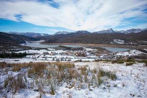 in riva al lago villaggio nel il neve capped montagne foto