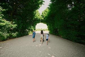 madre con bambini a piedi sotto alberi arco di giardino Schönbrunn palazzo nel vienna, Austria. foto