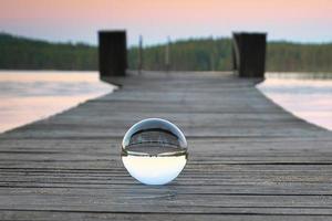 bicchiere palla su un' di legno passerella su un' svedese lago a il blu ora. natura Scandinavia foto